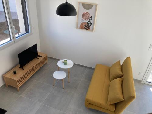 a living room with a couch and a tv and a table at Le gîte de la fontaine - le corbeau in Domblans
