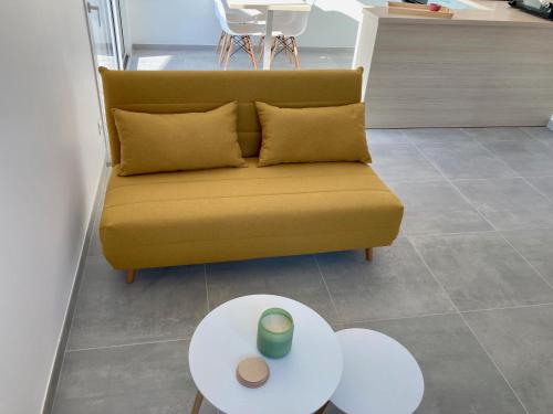 a yellow couch in a living room with a table at Le gîte de la fontaine - le corbeau in Domblans