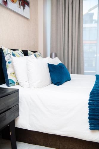 a bed with white sheets and blue pillows at Two-Bedroom Durban Point Waterfront Penthouse in Durban