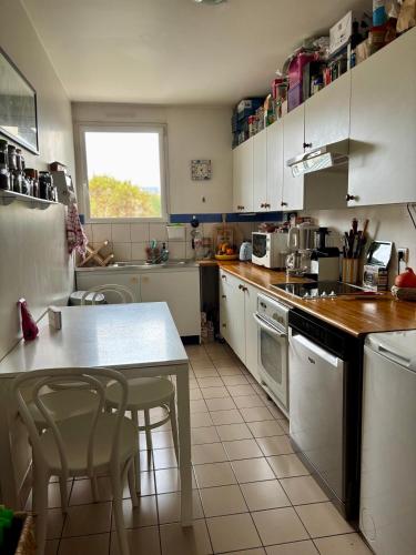 une cuisine avec des armoires blanches et une table et des chaises dans l'établissement Chambre calme et lumineuse en plein coeur de Paris, à Paris