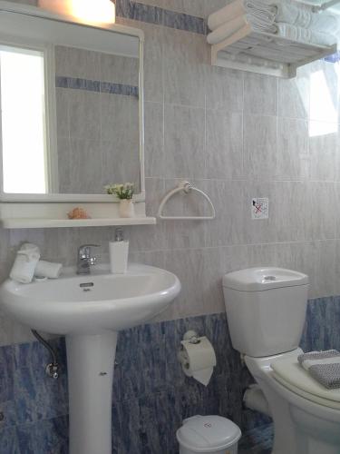 a bathroom with a sink and a toilet and a mirror at Kiklamino Sunset Studios in Oia