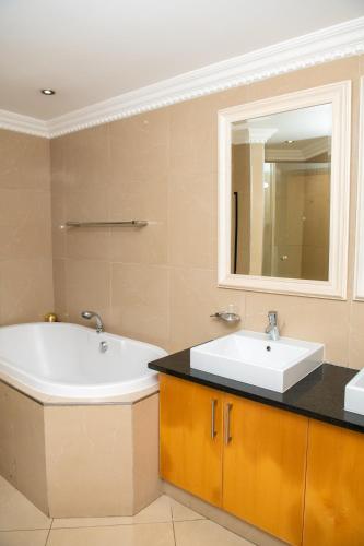 a bathroom with two sinks and a tub and a mirror at Two-Bedroom Durban Point Waterfront Penthouse in Durban