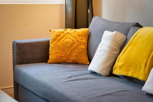 - un canapé bleu avec des oreillers jaunes dans l'établissement Le Rémi studio rénové au coeur de Rouen, à Rouen