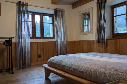 une chambre avec un lit et deux fenêtres dans l'établissement Maison à la montagne Bellevaux, à Bellevaux