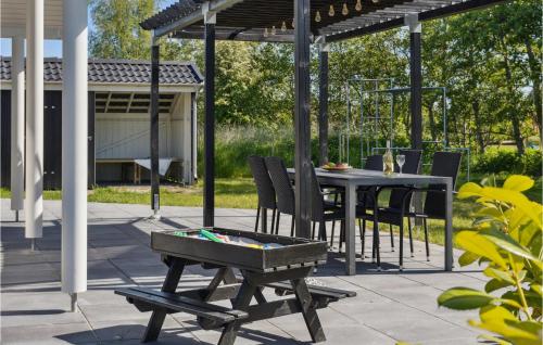 un patio con mesa y sillas bajo una pérgola en Beautiful Home In Idestrup With Sauna, en Bøtø By