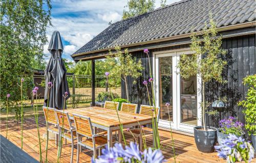 a wooden table and chairs on a deck with an umbrella at Two-Bedroom Holiday Home With A Fireplace In Sjællands Odde in Yderby