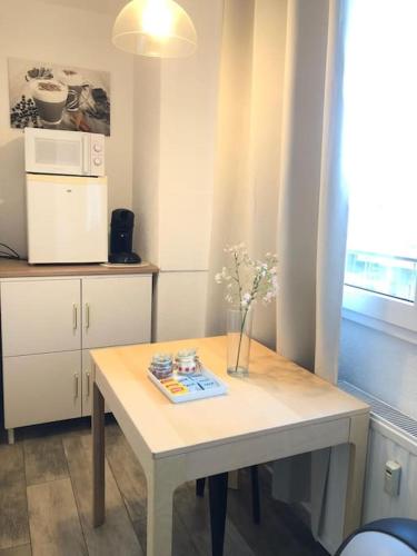 une cuisine avec une table avec un vase de fleurs dessus dans l'établissement Appart Chanael - Central, Balcon, à Saint-Louis