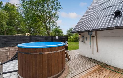 a hot tub on a deck next to a building at Cozy Home In Øster Assels With Sauna in Øster Assels