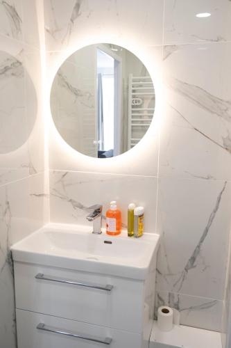 une salle de bain blanche avec un lavabo et un miroir dans l'établissement Appartement près du Vieux-Port, à Marseille