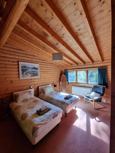 a bedroom with two beds and a chair in a room at Our Log House in the woods in Balnald