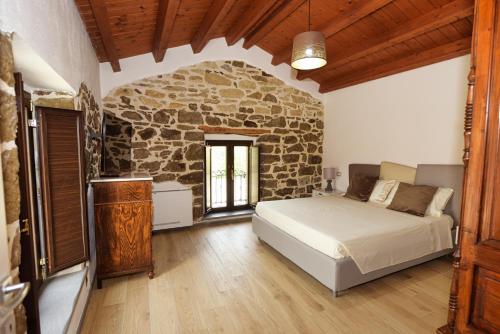 a bedroom with a bed and a stone wall at Casa di Nonna Rosa e Nonno Ciccito in Masullas