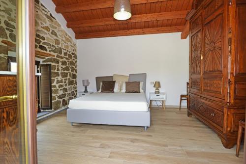 a bedroom with a white bed and a stone wall at Casa di Nonna Rosa e Nonno Ciccito in Masullas