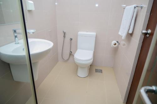 a white bathroom with a toilet and a sink at Family Friendly 3BR Apartment in Malabe, Colombo in Talahena