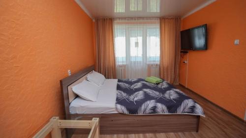 a small bedroom with a bed and a television at КУБА Апартаменты 1-ком в центре in Petropavlovsk