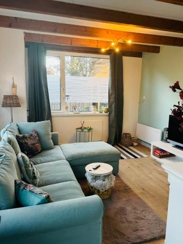 a living room with a blue couch and a table at Hello Noordwijk - Tiny House Dahliastraat 60 in Noordwijk aan Zee