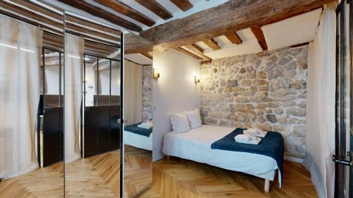une chambre avec un lit et un mur en pierre dans l'établissement 323 Suite Louis - Superbe Appartement à Paris, à Paris