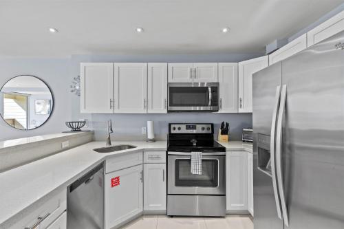 eine Küche mit weißen Schränken und einem Edelstahlkühlschrank in der Unterkunft Beachfront Resort 2BR Condo 3 Pools, Heated Pool, Kids Pool & Jacuzzi in South Padre Island