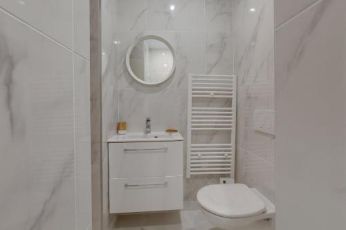 La salle de bains blanche est pourvue de toilettes et d'un miroir. dans l'établissement 140 Suite Ludo - Superbe Appartement à Paris, à Paris