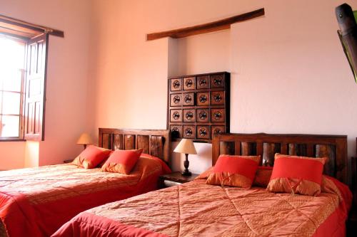 a bedroom with two beds with red pillows at Apart Hotel Loma Chica Quito in Quito