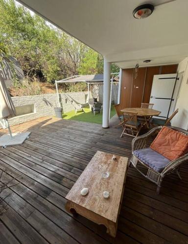 a wooden deck with a table and chairs on it at Ti Coin Boucan - Proche Plage in Boucan Canot