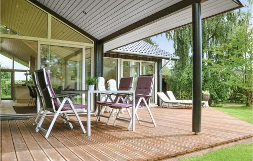 a wooden deck with a table and chairs on it at Three-Bedroom Holiday Home In Dronningmolle in Dronningmølle
