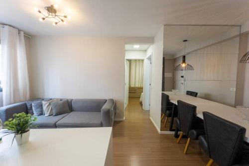 a living room and kitchen with a couch and a table at Apartamento Smart Encantador in Maringá