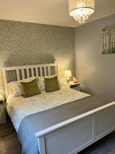 a bedroom with a large white bed with a chandelier at Modern 2 Bed Apartment in Oban