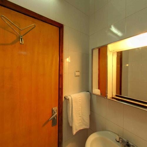a bathroom with a door and a sink and a mirror at GHION HOTEL in Addis Ababa