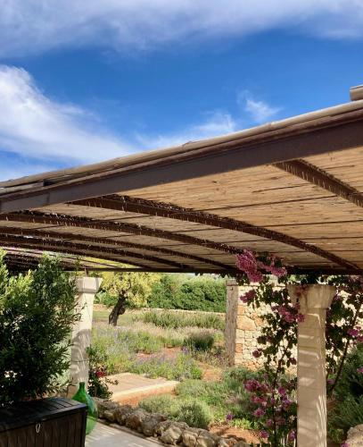 a wooden pergola with a garden in the background at Boutique Hotel Masseria Sottomasi in Savelletri di Fasano