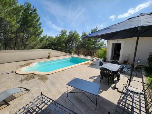 une piscine avec une table, des chaises et un parasol dans l'établissement Gite sur les hauteurs de Châteaurenard, à Châteaurenard