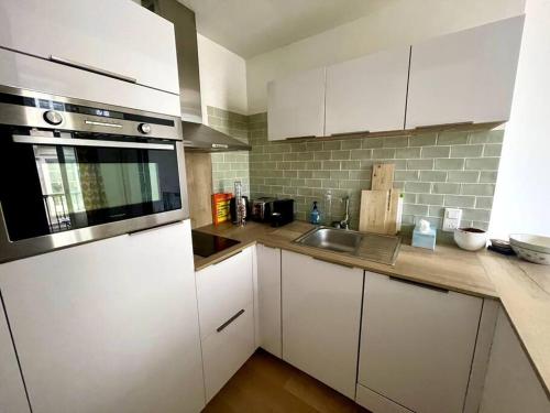a kitchen with white cabinets and a sink at Charmant appartement avec balcon - Jardin Public in Bordeaux