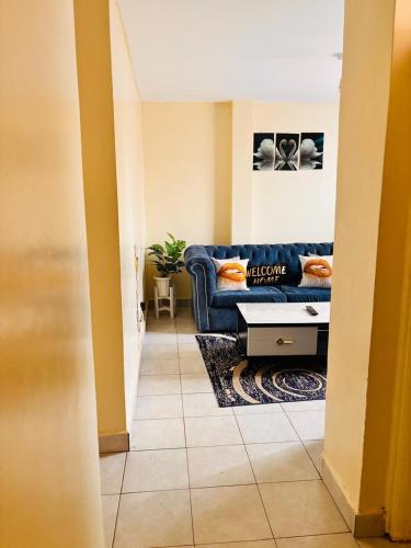 a living room with a blue couch and a table at Olive Homes Thika Town in Thika
