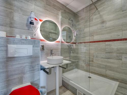 Un baño con lavabo y ducha de cristal. en Hotel de Belfort, en París