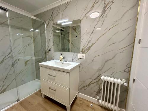 Un baño con lavabo blanco y ducha. en Rooms Cuenca, en Cuenca