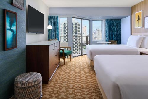 a hotel room with two beds and a television at Waikiki Malia in Honolulu