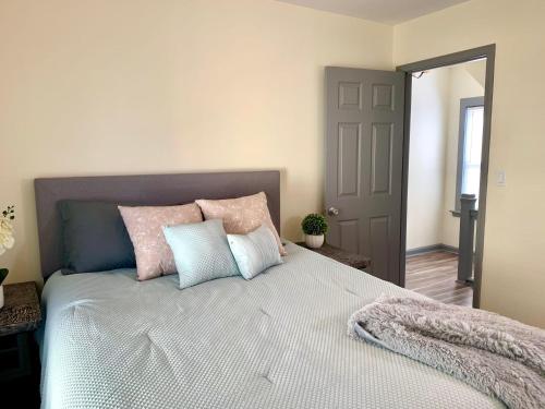 a bedroom with a large bed with pink and blue pillows at Cozy 3BR 1BA Short drive to Niagara Falls in Niagara Falls