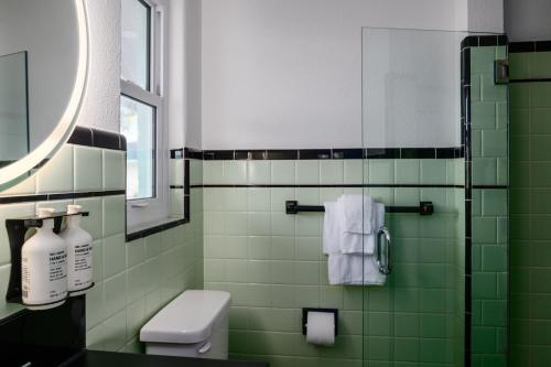 a green tiled bathroom with a toilet and a mirror at Haley's Court Boutique Motel in Saint Augustine
