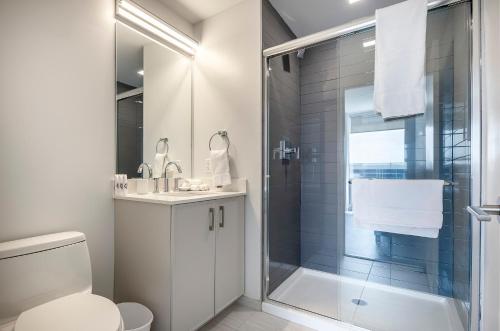 a white bathroom with a shower and a toilet at Luxury Apt with Gym & Pool in Stamford