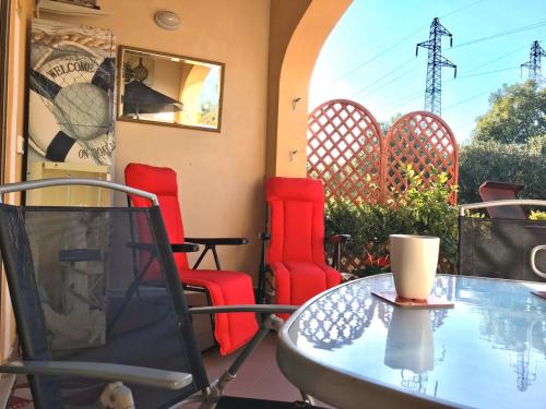 un patio con sillas rojas y una mesa de cristal en Pizzo Beach Studio 121G, en Pizzo