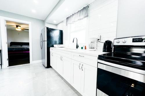 a kitchen with white cabinets and a black refrigerator at 2 Homes, 1 Stay-7BR Niagara Falls Compound in Niagara Falls