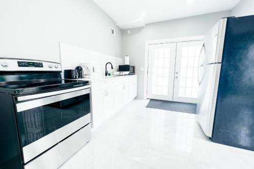 a white kitchen with a black stove and refrigerator at 2 Homes, 1 Stay-7BR Niagara Falls Compound in Niagara Falls