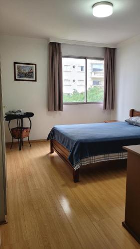 a bedroom with a bed and a table and a window at Quarto e banheiro privativos no Jardins in São Paulo