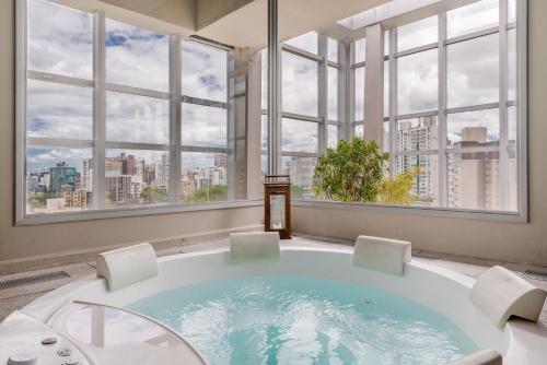 a large bath tub in a room with windows at Trend NCG - Apartament 1602 in Porto Alegre