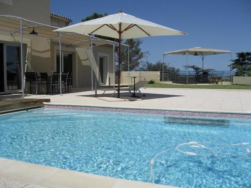 une piscine avec un parasol et un patio dans l'établissement Villa-piscine avec vue panoramique pour 2 à 10 personnes - PROMO 2025 Nouveaux tarifs affichés - moins 20 pour cent au 1er mai-, à Villeneuve-lès-Avignon