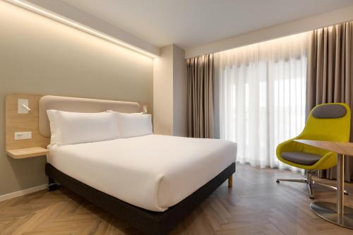 エヴォラにあるHoliday Inn Express Évora by IHGのベッドと黄色い椅子が備わるホテルルームです。