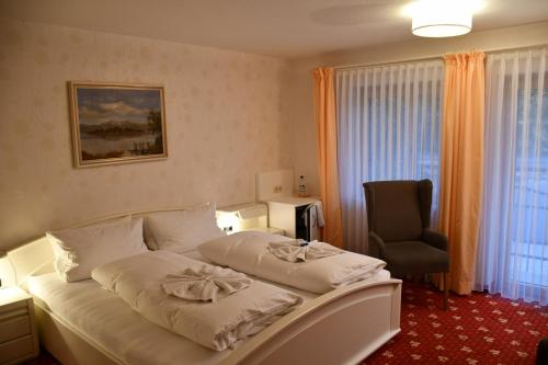 a hotel room with a bed and a chair at Pension Seeblick in Seebruck