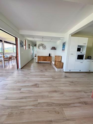 a living room with wooden floors and a kitchen at La villa Azur classée 3 étoiles Moderne et Confortable à deux pas de la plage de l Anse à l Ane Trois Îlets - Services Petit Dej sur demande in Les Trois-Îlets