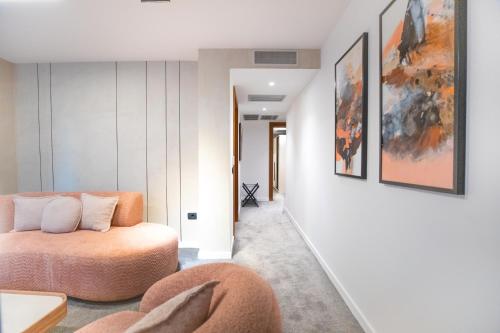 a living room with an orange couch and paintings on the wall at Metropol Hotel in Ferizaj