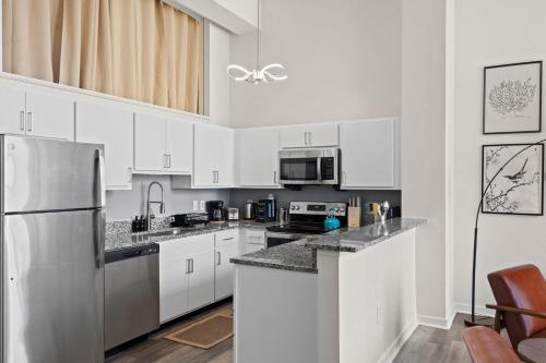 a kitchen with white cabinets and a stainless steel refrigerator at Indy Urban Nest - Sleeps 8 - Skywalk Access - Convention Center in Indianapolis