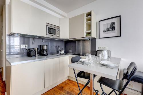 une cuisine avec des armoires blanches et une table avec des chaises dans l'établissement 310 Suite Petit Nid Douillet Apartment in Paris, à Paris